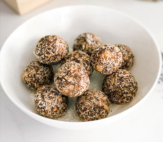 White bowl with rolled energy bites coated in coconut and made with Navitas Organics Chia Seeds