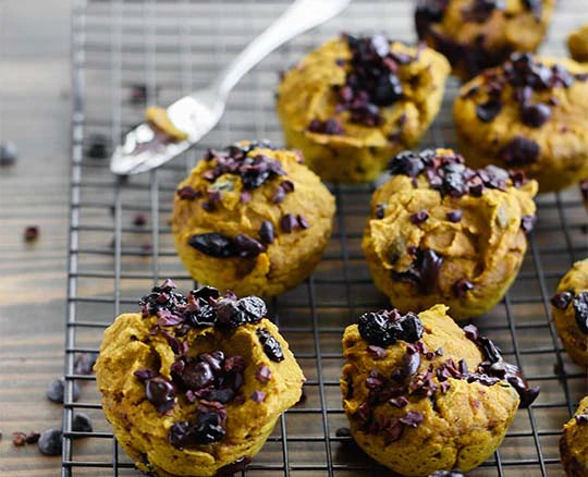 Pumpkin cacao muffins on a cooling rack sprinkled with Navitas Organics Cacao Nibs