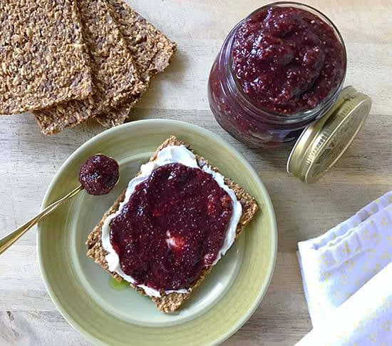 Seed crackers spread with cream cheese and superfood berry chia jam