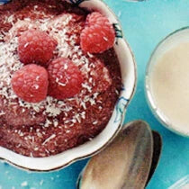 Bowl of superfood berry and cacao mousse topped with raspeberries and shredded coconut