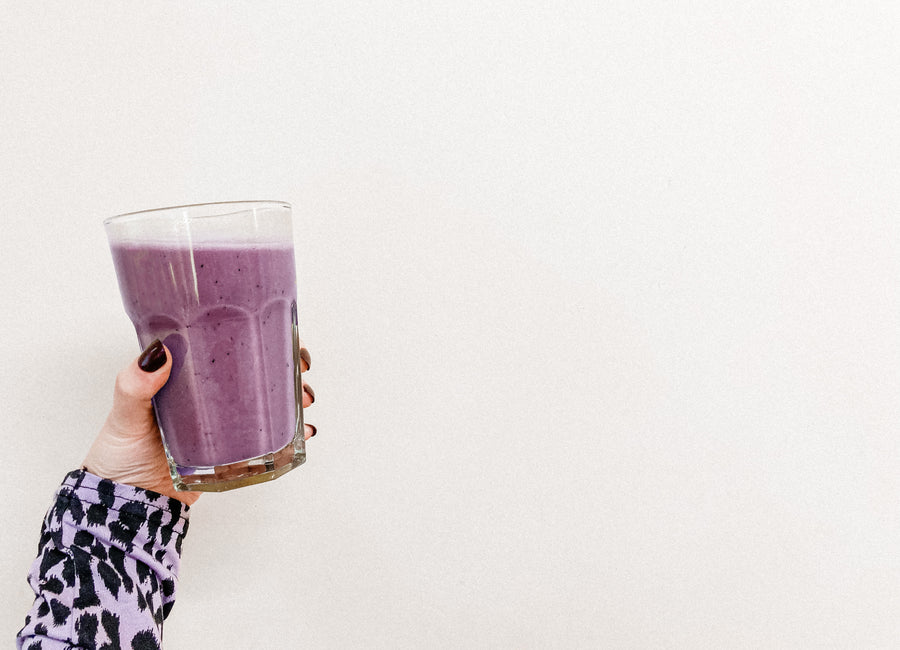 Purple maqui berry smoothie being help up in a glass