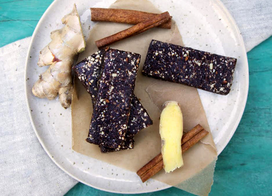 Energy bars made with Navitas Organics Acai Powder on a plate with cinnamon sticks and fresh ginger