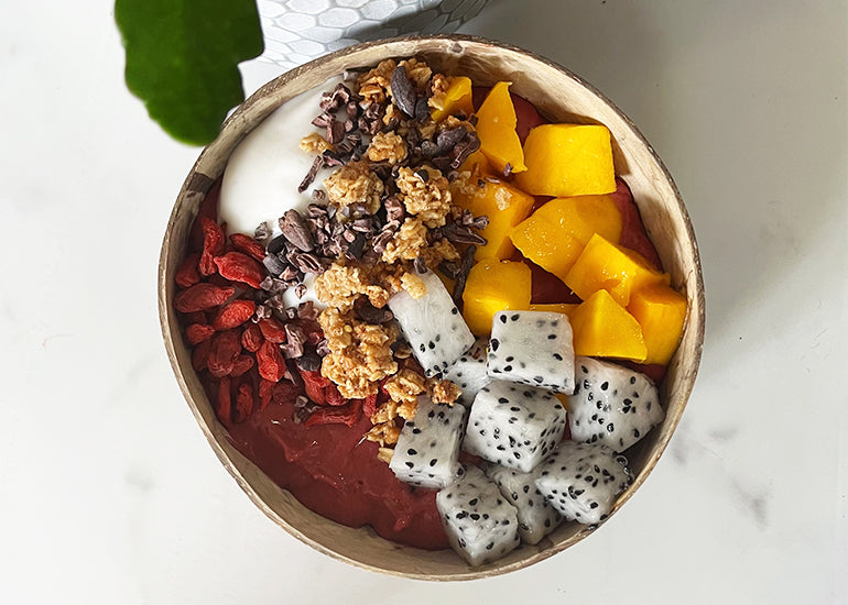A smoothie bowl made with Navitas Organics Camu Powder topped with diced mango, dragonfruit, Navitas Organics Goji Berries and Navitas Organics Cacao Nibs