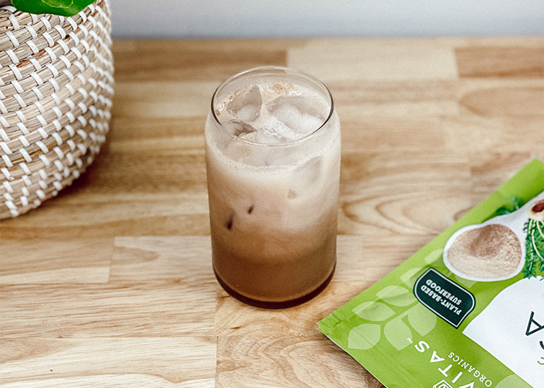 An iced maca latte made with Navitas Organics Maca Powder and Cacao Powder in a tall glass with a straw