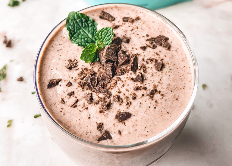 A mint chocolate smoothie made with Navitas Organics Chia Seeds and Hemp Seeds, topped with chopped dairy-free chocolate and fresh mint
