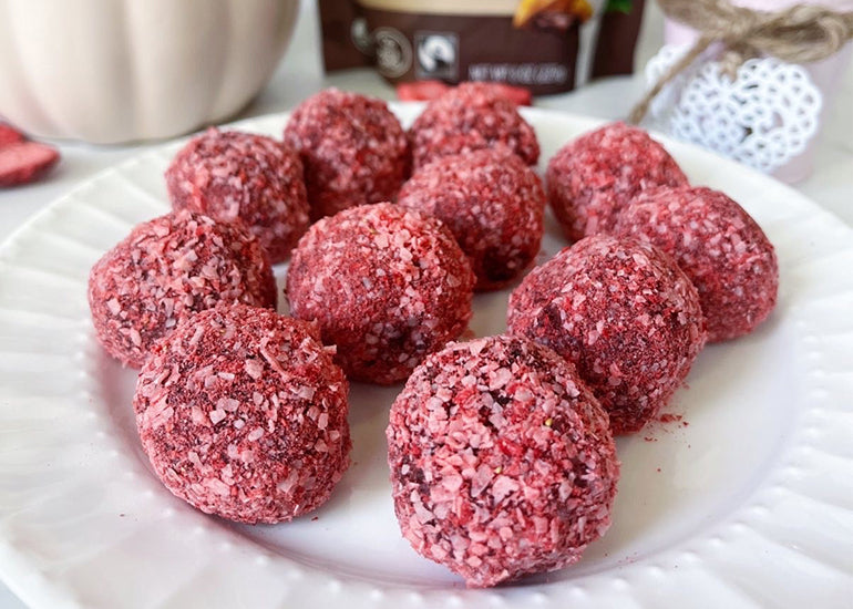 A plate full of truffles made with Navitas Organics Cacao Powder, raspberries, coconut, and other plant-based ingredients