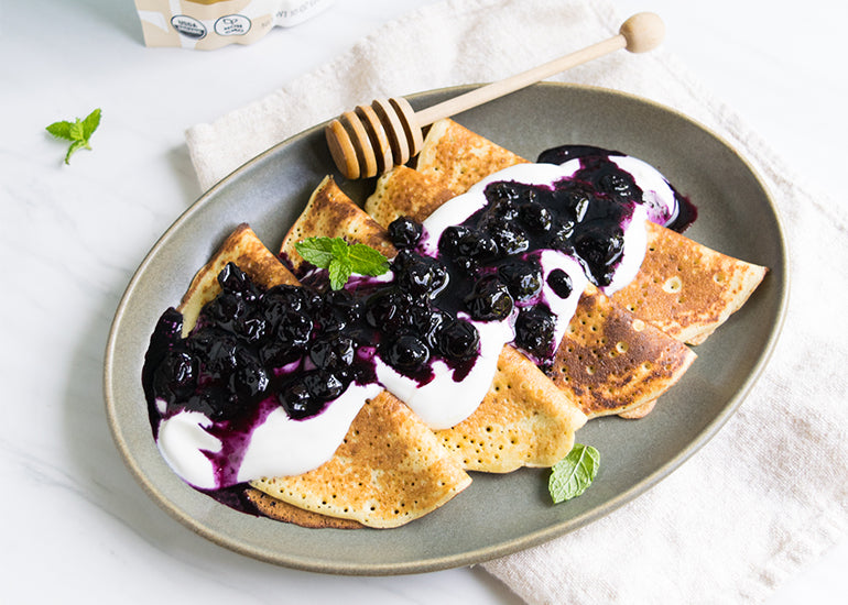 A plate full of crepes made with Navitas Organics Chickpea Flour, topped with yogurt, blueberries and honey