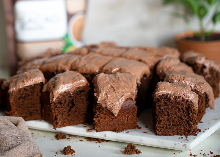 Cut squares of a chocolate sheet cake made with Navitas Organics Cacao Powder, topped with a chocolate buttercream frosting made with Navitas Organics Cacao Powder