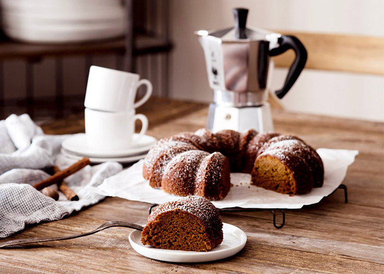 A loaf of brown butter pumpkin cake made with Navitas Organics Grain-Free Flour on a table with tea