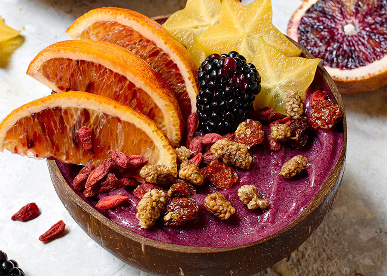 A smoothie bowl made with Navitas Organics Superfood+ Berry Blend, topped with fresh fruit and Navitas Organics Goji Berries, Mulberries and Goldenberries