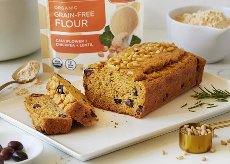 A loaf of rosemary olive bread made with Navitas Organics Grain-Free Flour sliced and sitting atop a serving dish
