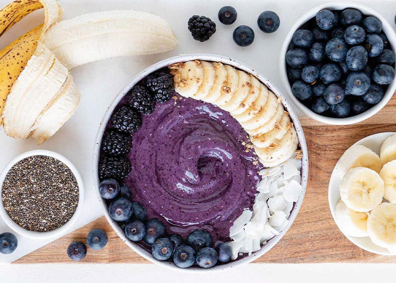 A smoothie bowl made with blueberries, bananas and Navitas Organics Chia Seeds, topped with fresh berries, banana slices and coconut flakes
