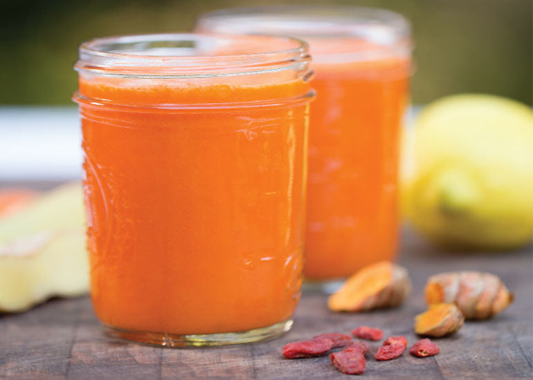 Two mason jars filled with orange juice made with Navitas Organics Turmeric Powder, Camu Powder and Goji Powder