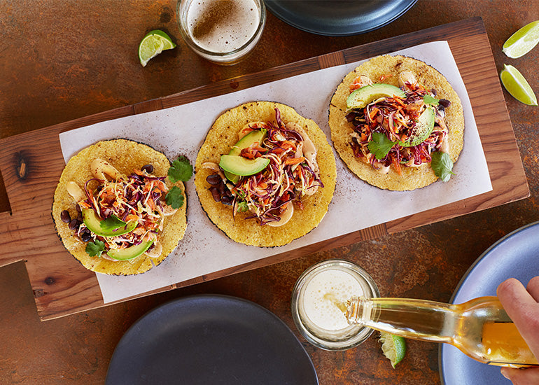 A row of tacos topped with slaw made with Navitas Organics Goldenberries, garnished with a cream sauce made with Navitas Organics Cashew Nuts