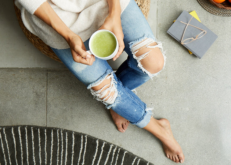 A woman holding a mug filled with a matcha latte made with Navitas Organics Matcha Powder