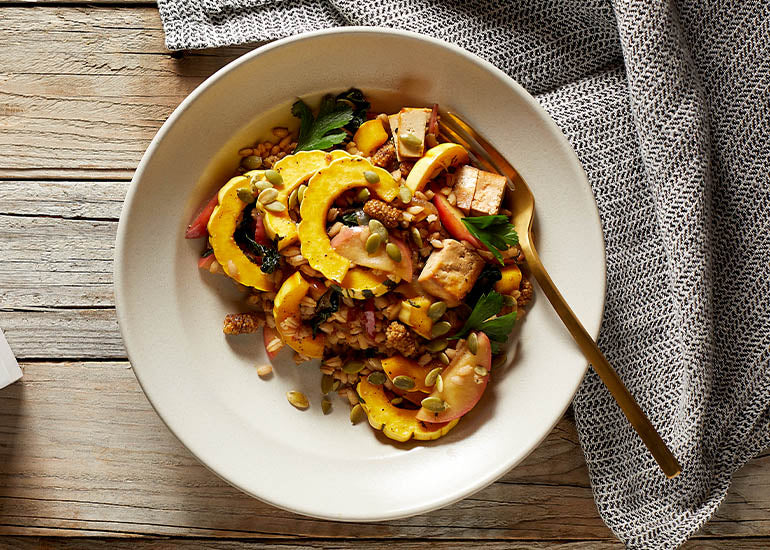 A bowl filled with squash, barley, tofu and Navitas Organics Mulberries