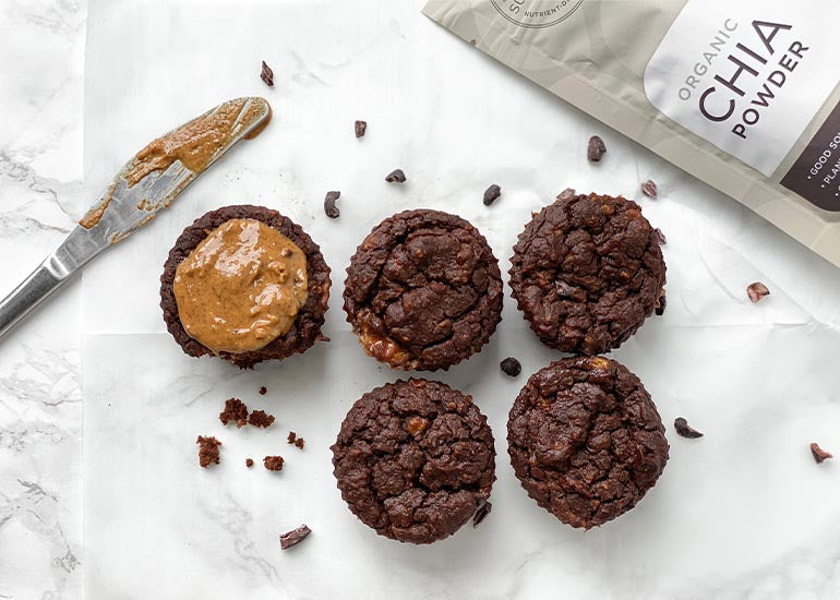 Rows of chocolate muffins made with Navitas Organics Chia Powder and Cacao Powder, topped with a nut butter spread