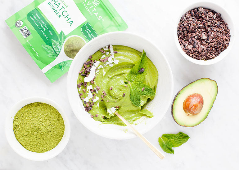 A green smoothie bowl made with Navitas Organics Matcha Powder and Superfood+ Greens Blend, topped with Navitas Organics Cacao Sweet Nibs, coconut flakes and fresh mint leaves