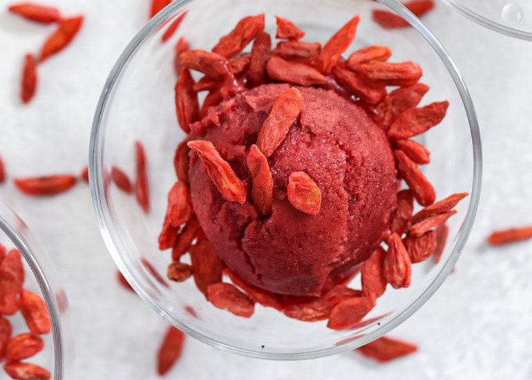 A glass dish filled with cherry superfood sorbet, made with Navitas Organics Superfood+ Immunity Blend and topped with Navitas Organics Goji Berries