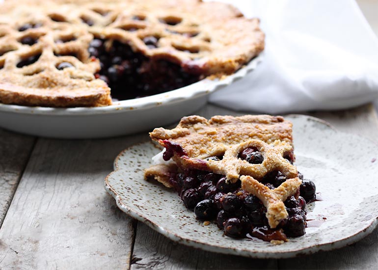 A full blueberry goji pie made with Navitas Organics Goji Berries with a slice served on a plate