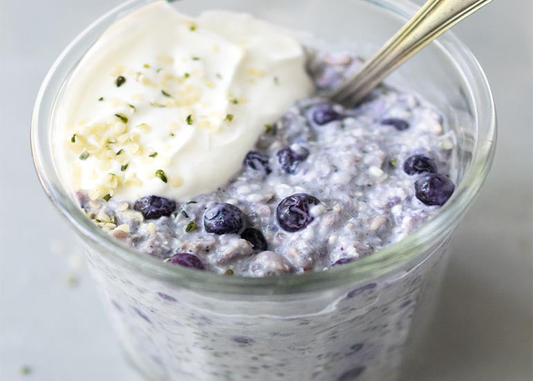 A jar filled with blueberry hemp overnight oats made with Navitas Organics Hemp Seeds and Chia Seeds.