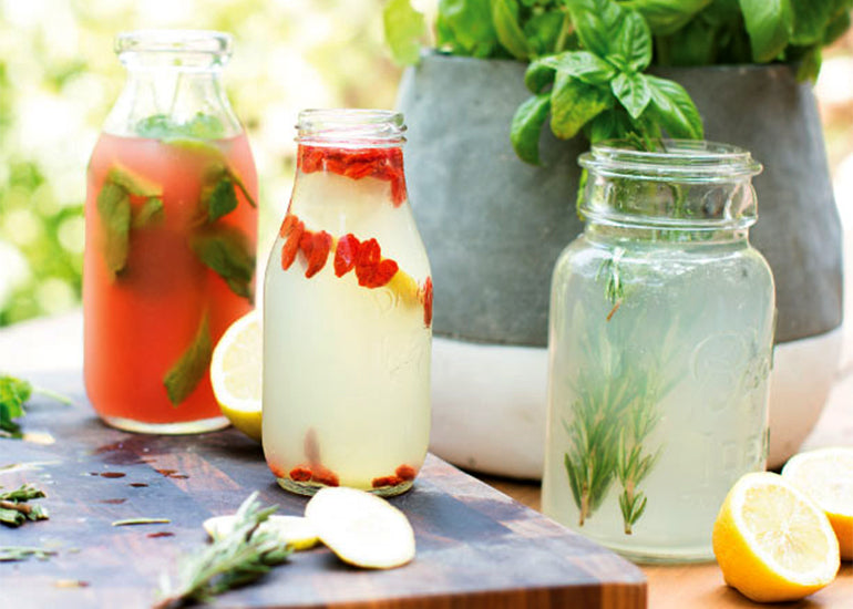 Three glass containers filled with different types of superfood lemonade including camu lemonade made with Navitas Organics Camu Powder and Goji Berries.