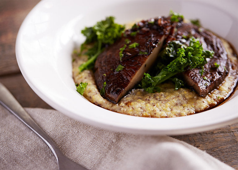 A bowl of chia polenta made with Navitas Organics Chia Seeds, topped with a grilled Portobello mushroom and sautéed kale.