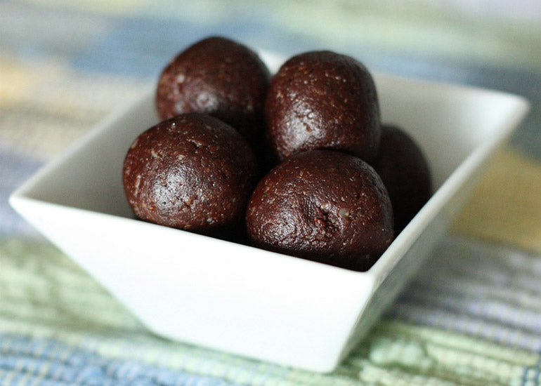 A dish filled with chocolate energy bites made with Navitas Organics Cacao Powder, Maca Powder and Hemp Seeds.