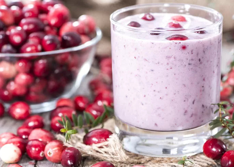 A glass filled with a pink cranberry smoothie made with Navitas Organics Goji Berry Powder.