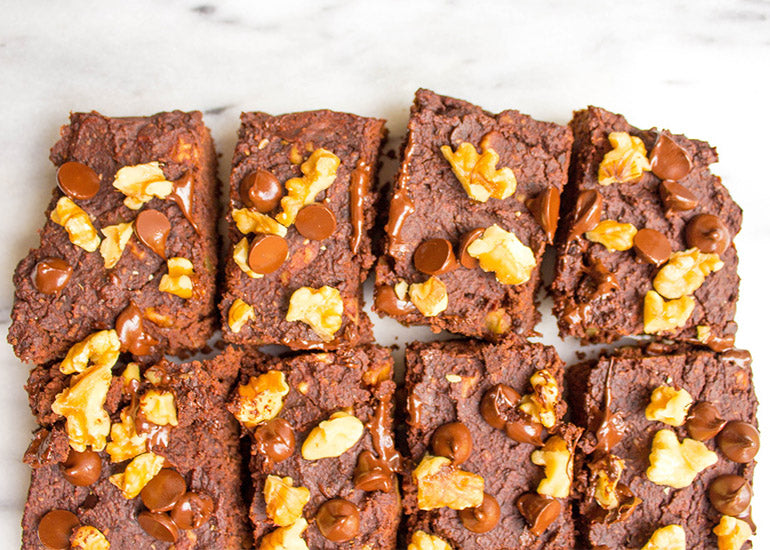 Rows of fudgy brownies made with Navitas Organics Chia Seeds and Cacao Powder, topped with chocolate chips and nuts.