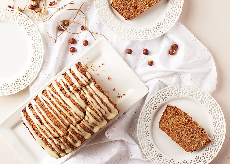 A goldenberry hazelnut loaf cake made with Navitas Organics Chia Powder and Goldenberries on a dish with slices served on smaller plates.