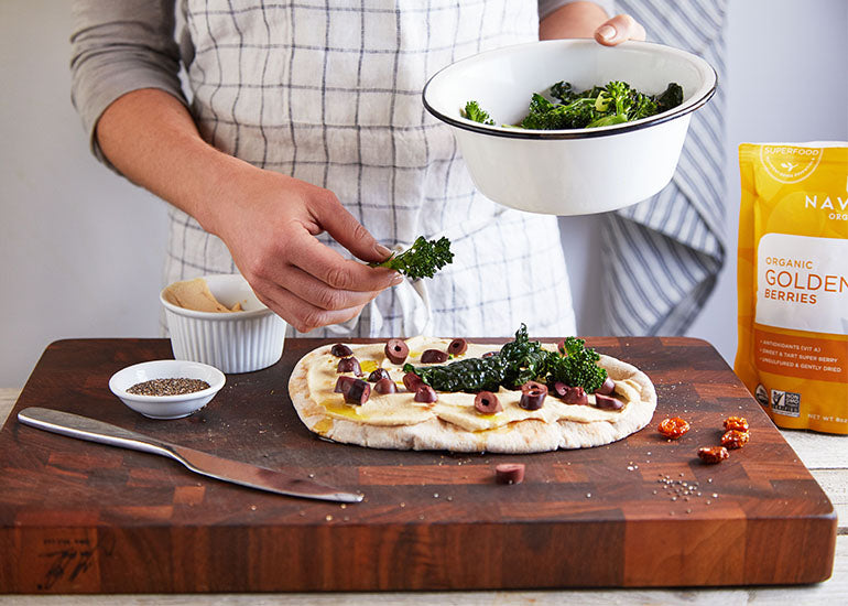 A woman making a pizza with Navitas Organics Chia Seeds and Goldenberries.