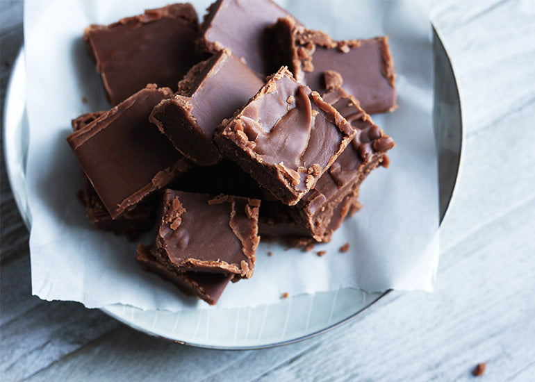 A plate topped with squares of cacao nut butter fudge made with Navitas Organics Cacao Wafers.