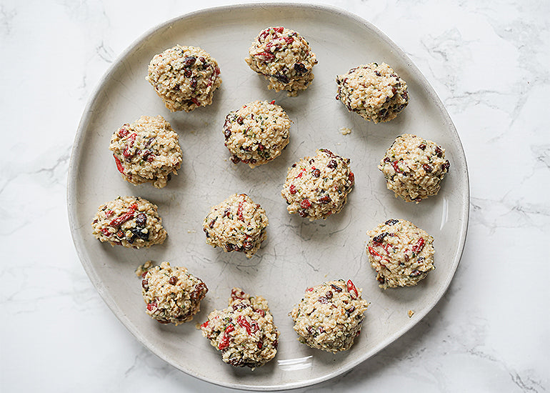 A plate topped with tahini energy bites made with Navitas Organics Cacao Sweet Nibs, Hemp Seeds, Goldenberries and Goji Berries.