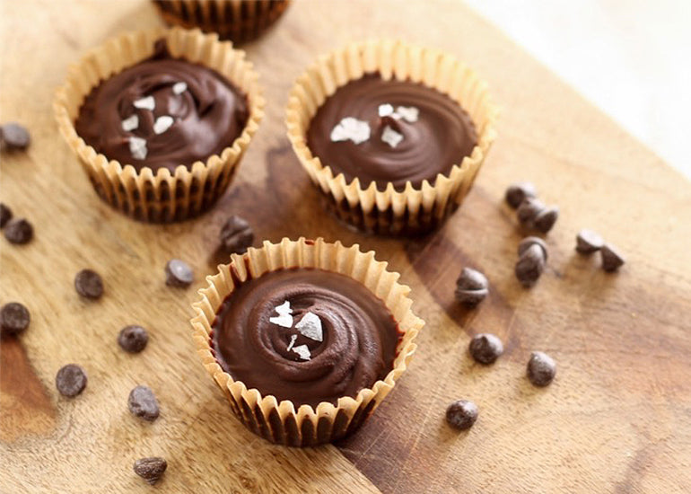 Mini chocolate peanut butter cups made with Navitas Organics Maca Powder on a cutting board, topped with sea salt.