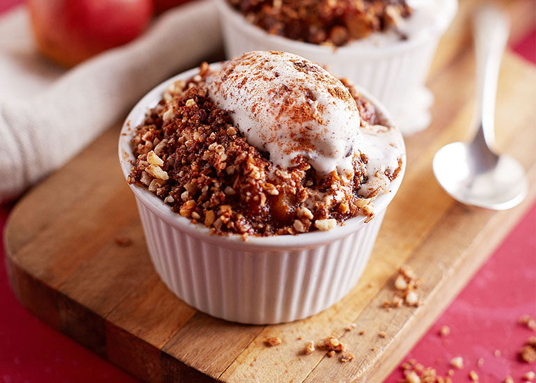A mulberry pear crisp made with Navitas Organics Mulberries in a ceramic serving dish, topped with coconut yogurt and cinnamon.