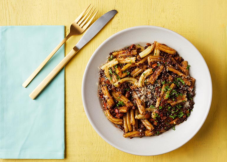A plate of pasta topped with a lentil Bolognese sauce mixed with Navitas Organics Goji Berries.