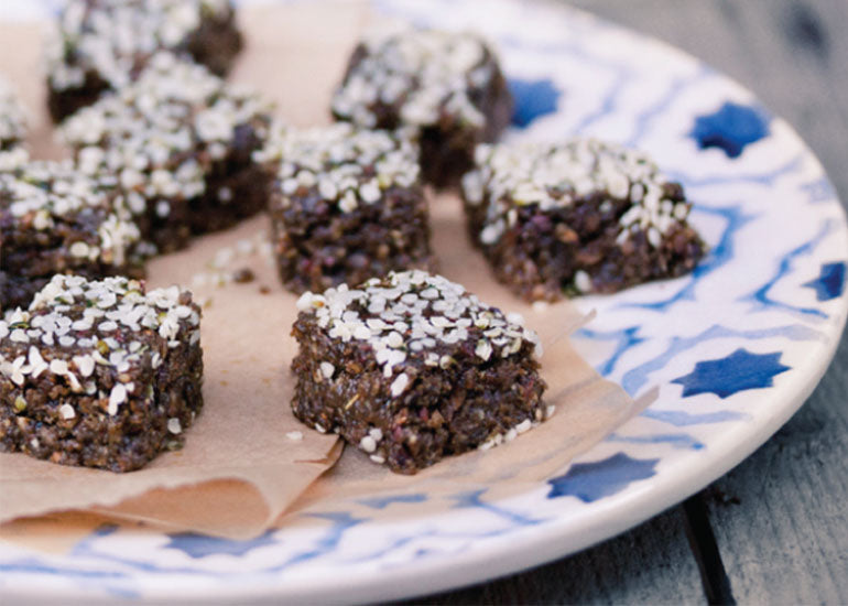 A plate of pecan-hemp protein bites made with Navitas Organics Hemp Powder, Mulberries and Cacao Nibs, sprinkled with Navitas Organics Hemp Seeds.
