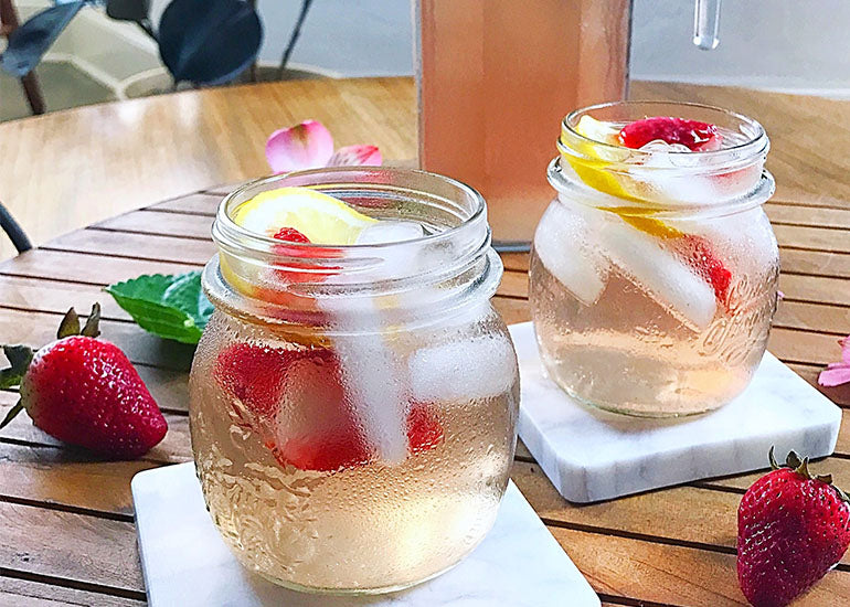 Two mason jars filled with a pink pomegranate lemon water made with Navitas Organics Pomegranate Powder.