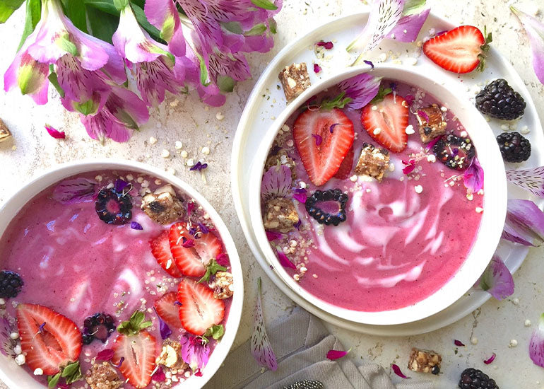 Two pitaya goji acai bowls made with Navitas Organics Acai Powder and Goji Powder, topped with Navitas Organics Hemp Seeds and berries.