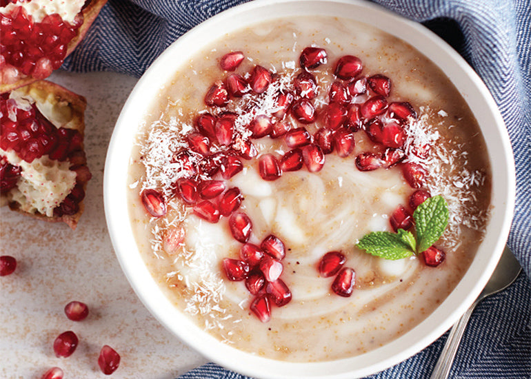 A bowl of pomegranate amaranth porridge made with Navitas Organics Pomegranate Powder, topped with fresh pomegranate seeds.