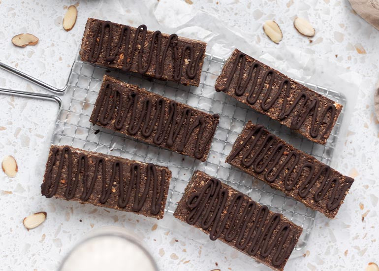 A cooling rack topped with chocolate date energy bars made with Navitas Organics Cacao Wafers and Hemp Powder.
