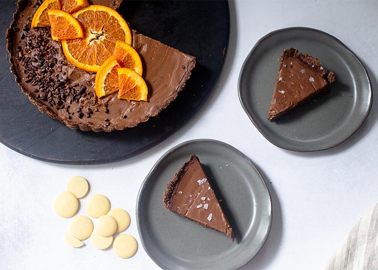 An orange chocolate tart made with Navitas Organics Cacao Butter Wafers, Cacao Powder, Cacao Nibs and Cacao Sweet Nibs.