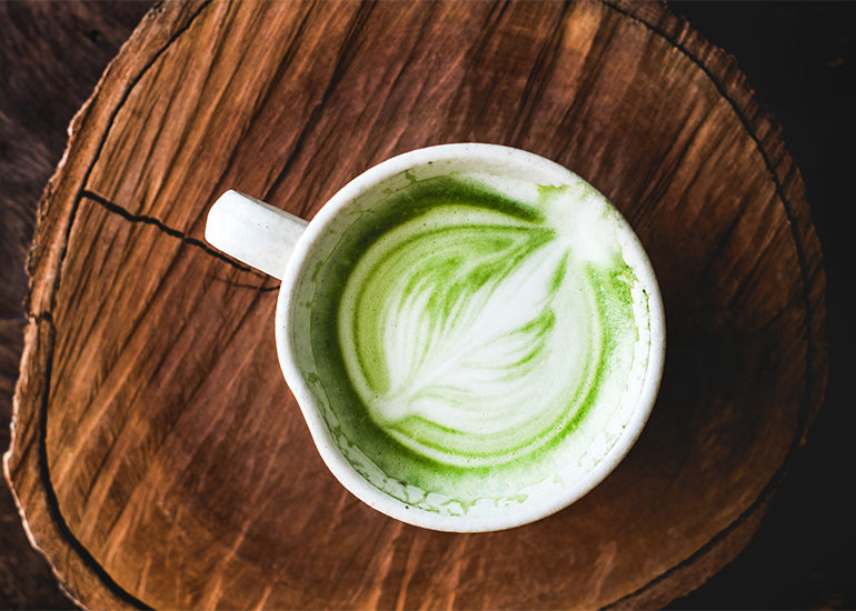 A matcha latte made with Navitas Organics Matcha Powder on a wooden board.