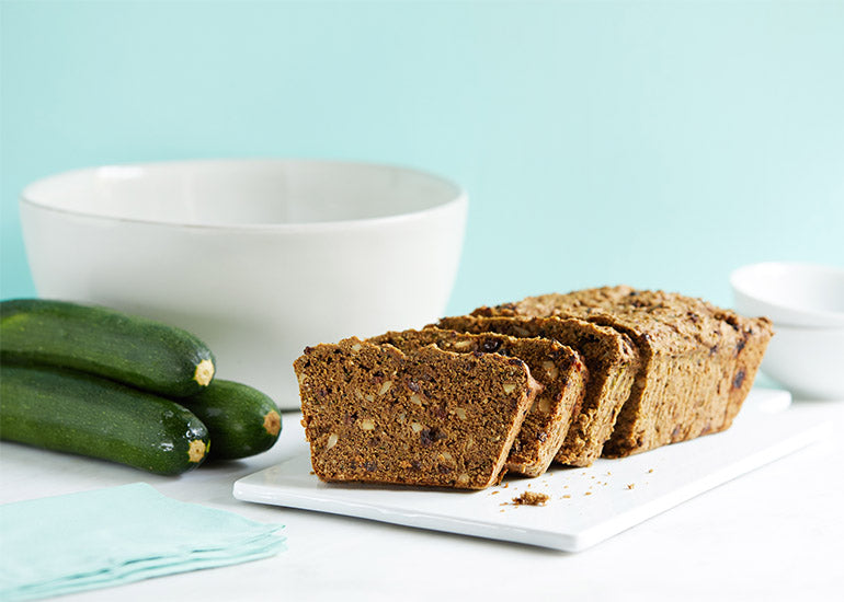 A sliced loaf of zucchini bread made with Navitas Organics Vanilla & Greens Essential Blend Protein Powder, Chia Powder and Hemp Seeds.