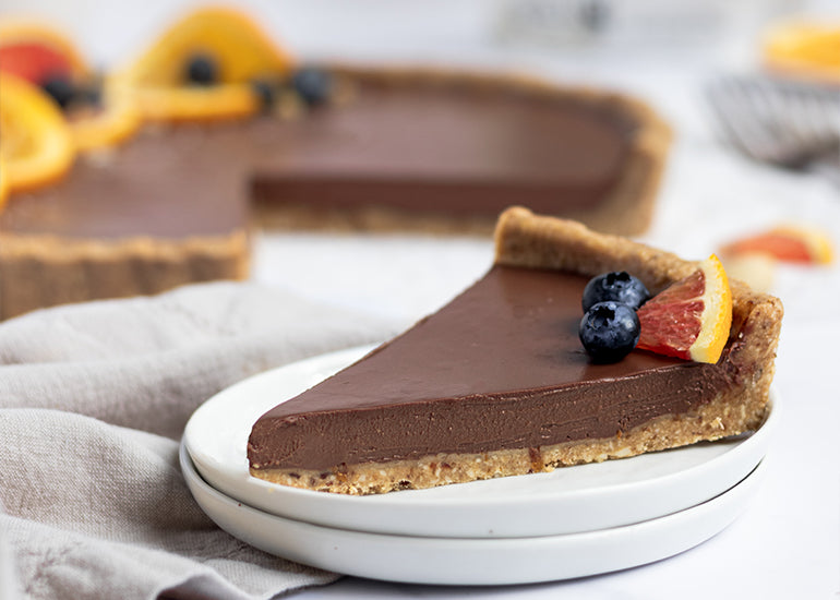A no-bake chocolate orange tart made with Navitas Organics Cashew Nuts and Cacao Butter Wafers