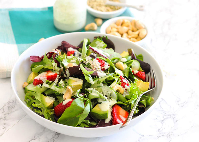 A strawberry avocado salad with a hemp tahini dressing made with Navitas Organics Cashew Nuts and Hemp Seeds.