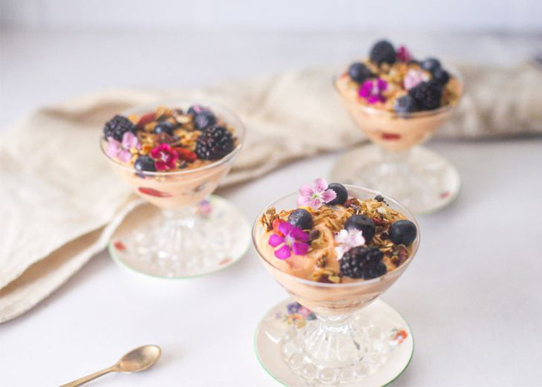 Superfood yogurt and fruit parfaits made with Navitas Organics Cacao Butter Wafers, Hemp Seeds, Goji Berries, Cacao Nibs, Maca Powder and Goji Powder, topped with fresh flowers.