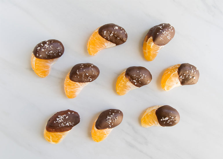 Chocolate-dipped mandarins made with Navitas Organics Cacao Powder sprinkled with sea salt.