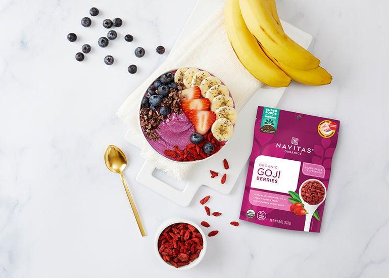 A fruit smoothie bowl made with Navitas Organics Goji Berries, topped with fresh fruit and Navitas Organics Cacao Nibs, Goji Berries and Chia Seeds